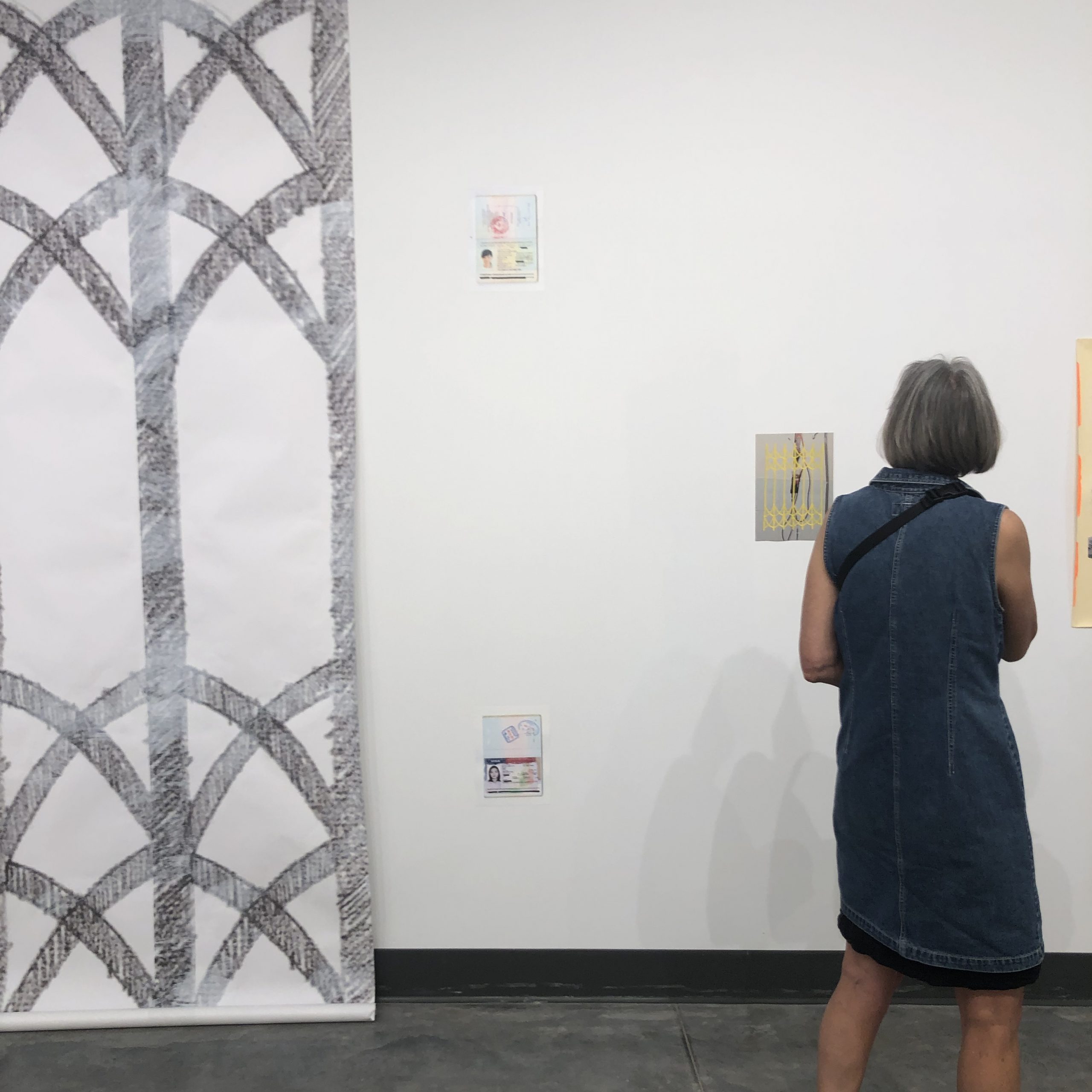 person viewing an art exhibition with large and small drawings on the wall