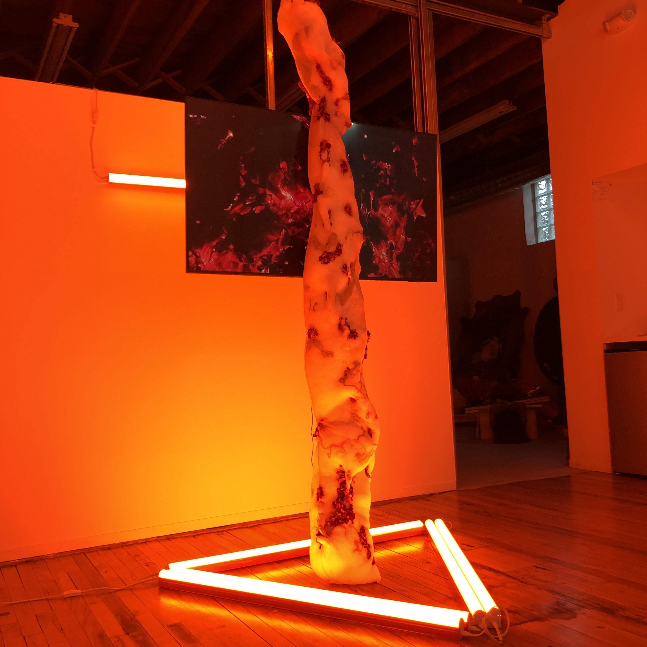 an orange lit installation featuring a video screen