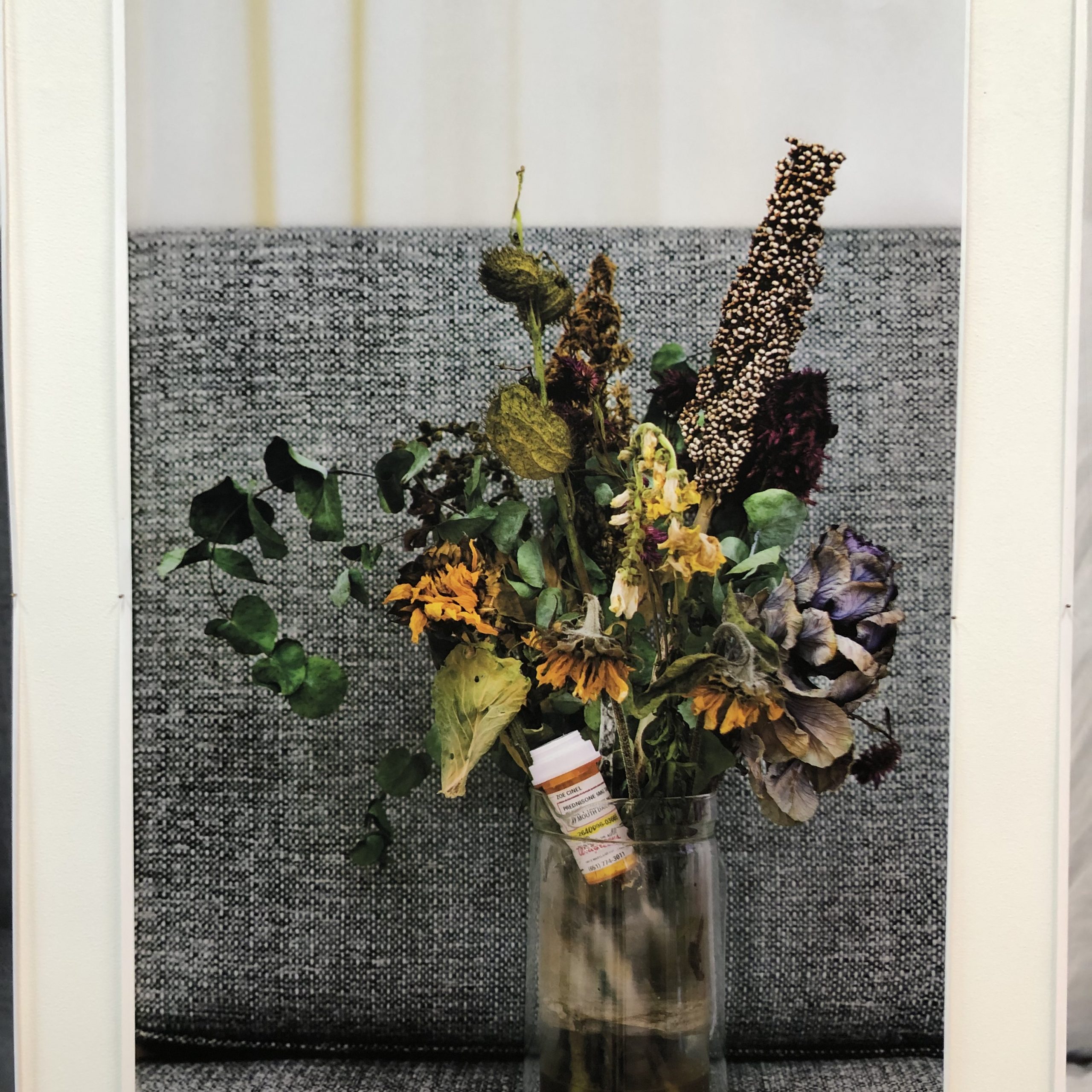 detail of photo with dying flowers and medicine bottle