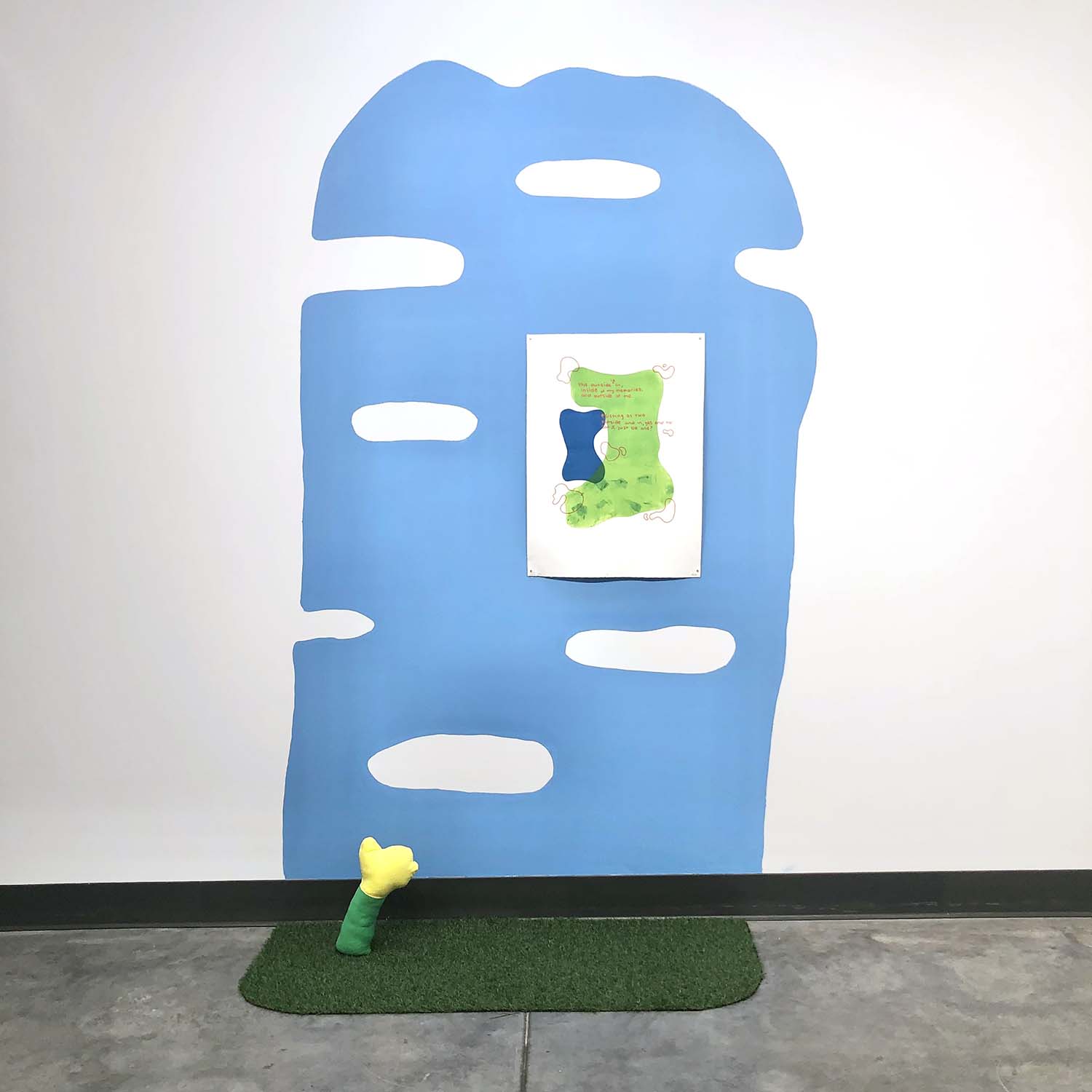 installation with blue painted wall, print and fake grass
